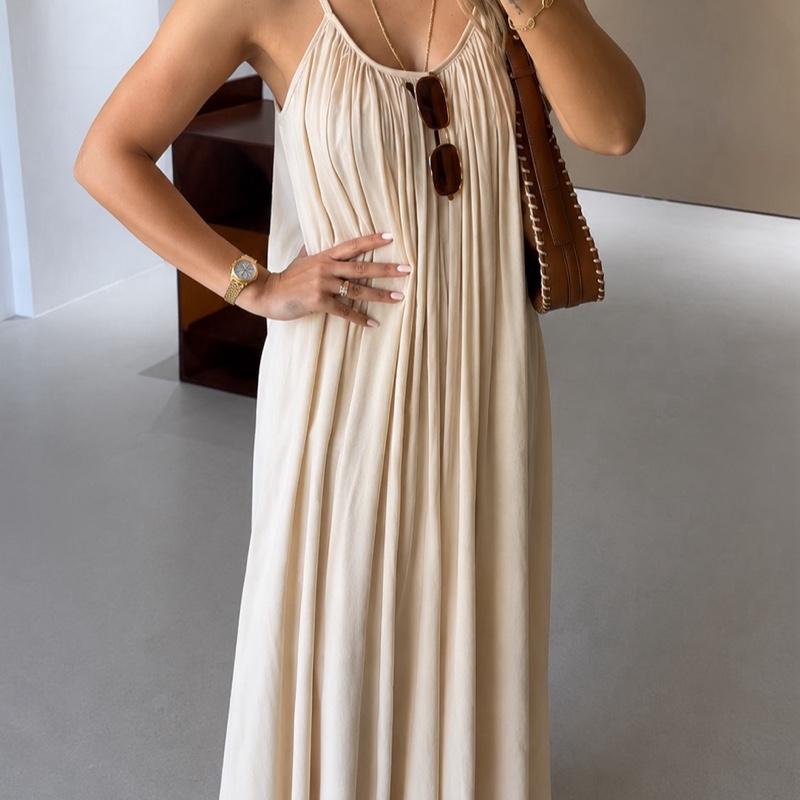 Femme portant une robe maxi beige sable à fines bretelles avec coupe ample et tissu fluide élégant.