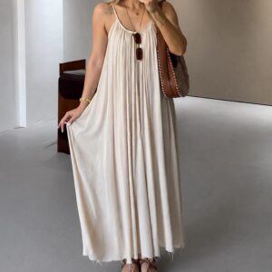 Femme portant une robe longue écrue fluide à fines bretelles avec coupe ample et tombé léger.