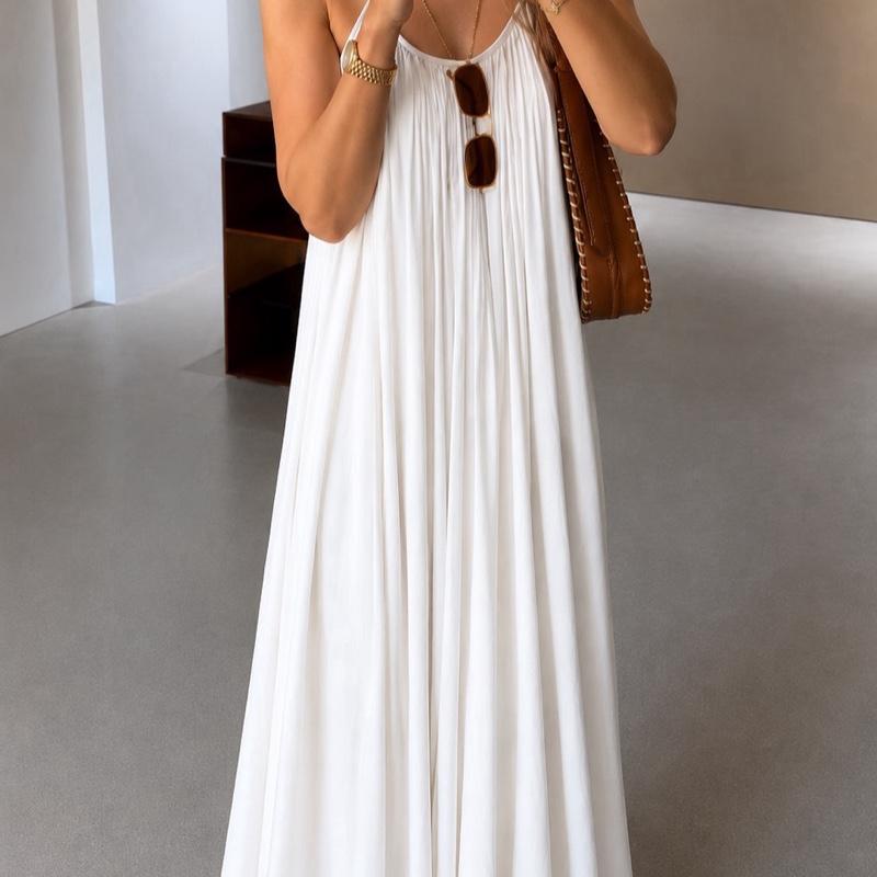 Détail d'une robe longue blanche plissée à fines bretelles avec coupe ample et tombé fluide.